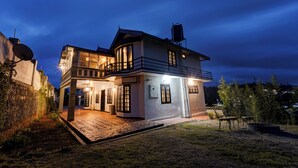 A two-story house with a balcony, a satellite dish, and a paved driveway. - Alaya Stays Cleft 3BHK with Garden (Kotagiri)