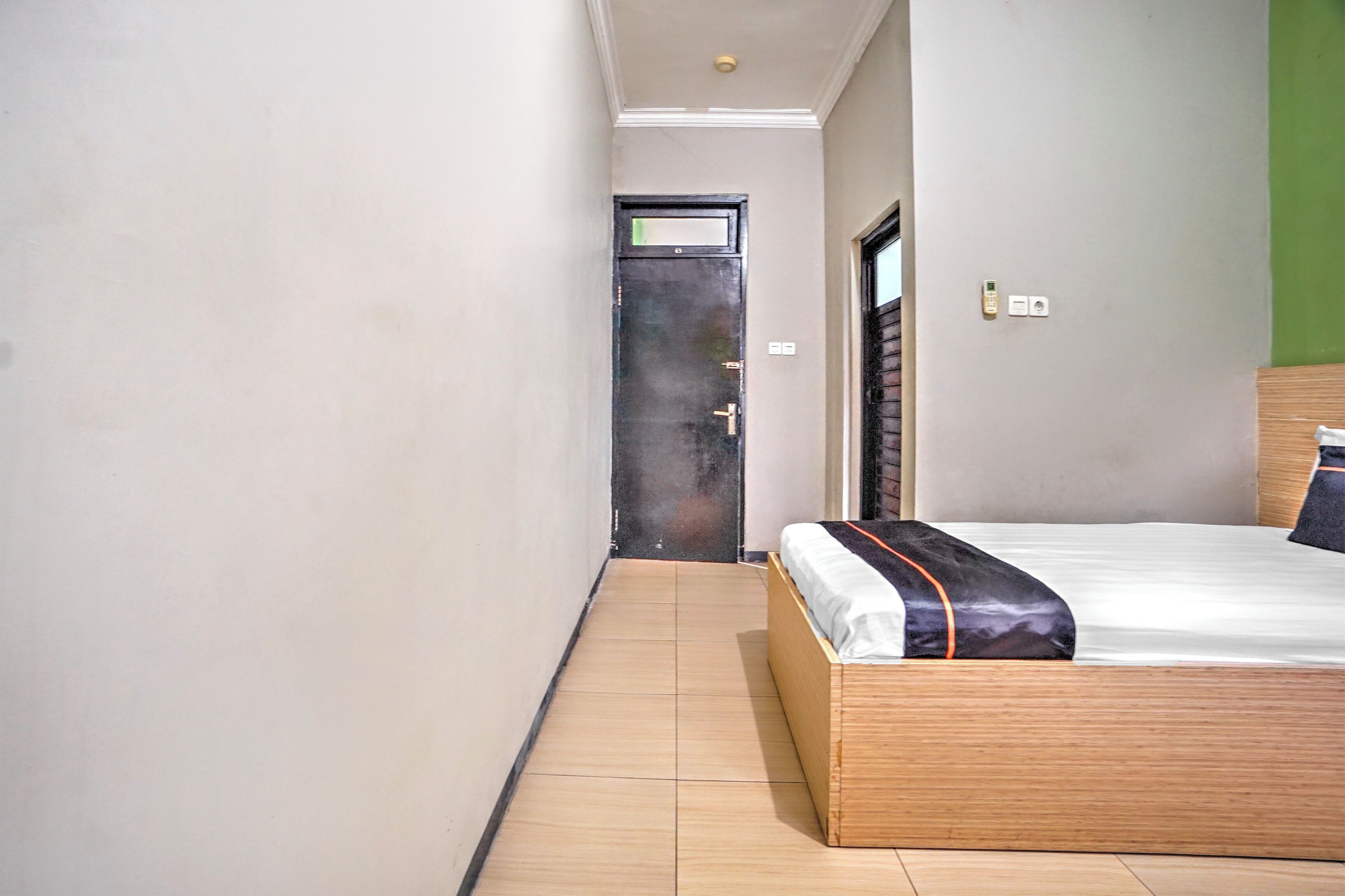 Une chambre d’hôtel avec un lit en bois, une porte et un mur vert.