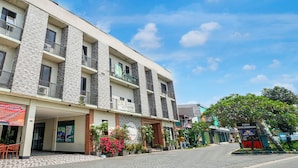 A multi-story hotel with balconies, a covered entrance, and a paved street. - Hotel O near Juanda Airport formerly Azz (Sidoarjo)