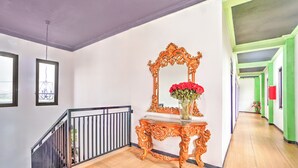 A hallway with a staircase, a decorative mirror, and a vase with flowers. - Hotel O near Juanda Airport formerly Azz (Sidoarjo)