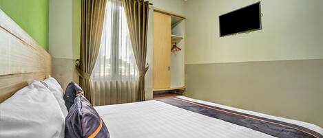 Habitación de hotel con cama, armario, televisor y ventana con cortinas.