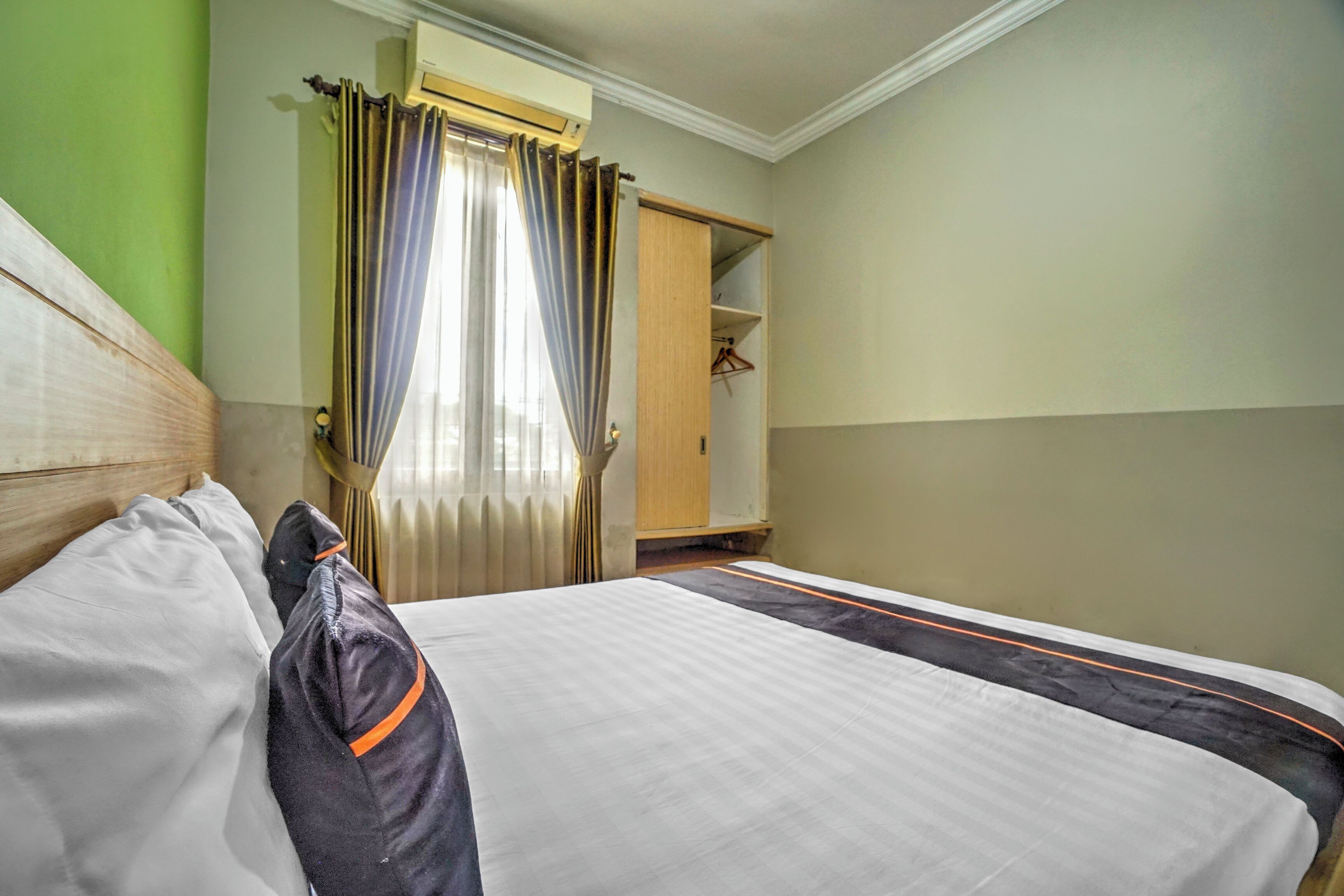 A hotel room with a bed, a wardrobe, and a window with curtains.