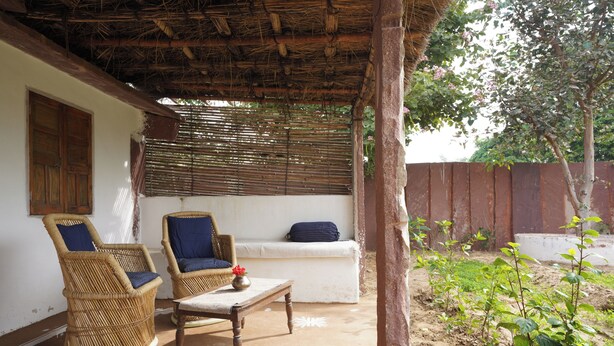 A covered outdoor seating area with wicker chairs, a sofa, and a table.