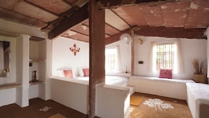 A room with a bed, a window with bars, a wall decoration, and a ceiling fan.