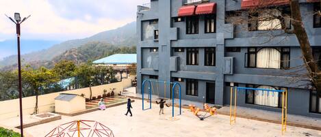 A building with multiple floors, outdoor play area, and a view of the surrounding landscape.