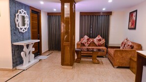 A living room with a sofa, a coffee table, a side table, a decorative mirror, and a door. -  Shivraj Hotel Mussoorie (Mussoorie)