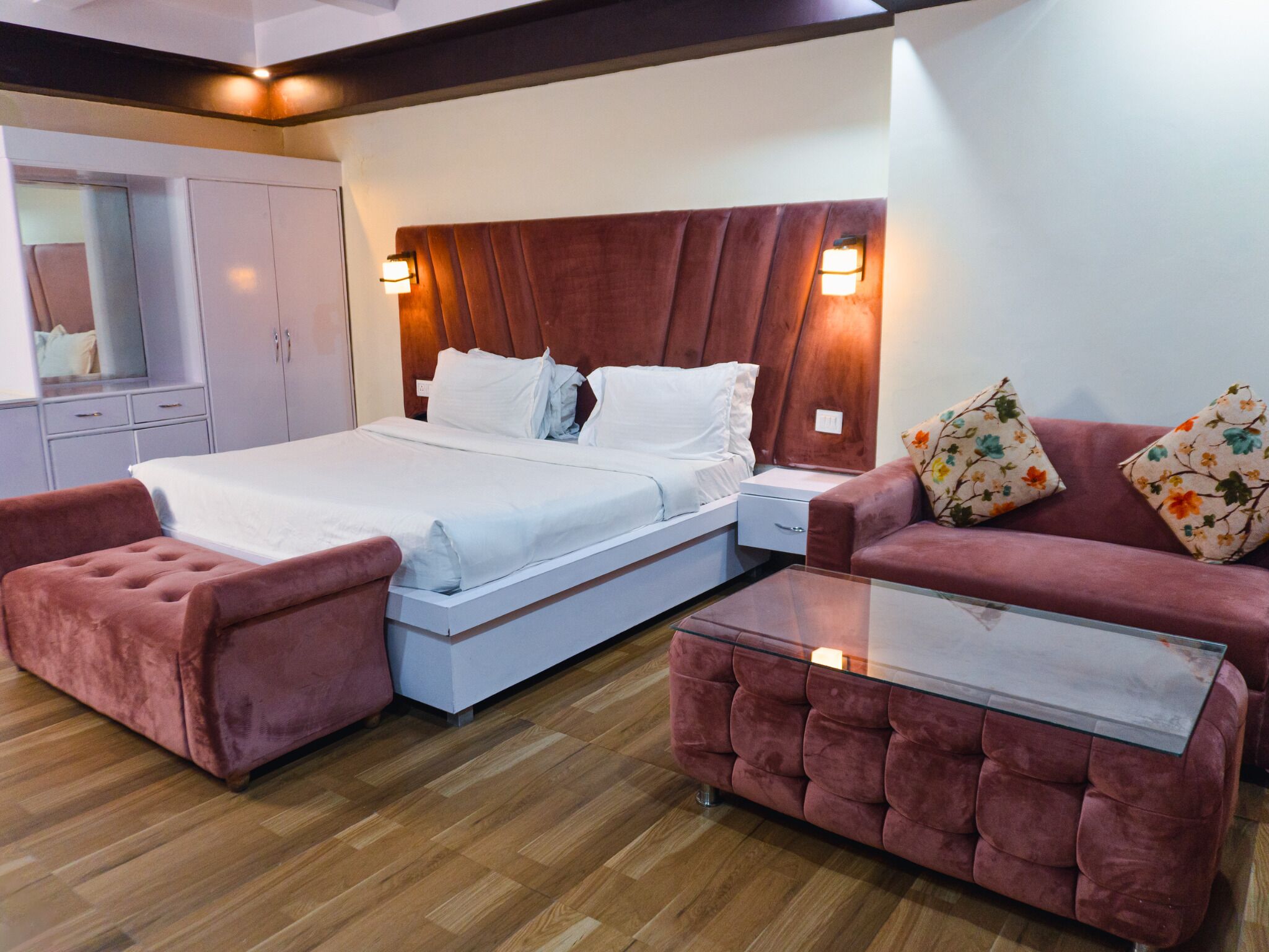 A hotel room with a bed, a sofa, a small table, and a wardrobe.