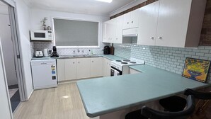 A compact kitchen with white cabinets, a microwave, a toaster, and a stove.