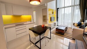 Un salon moderne comprenant un coin repas, une cuisine avec un revêtement mural jaune et une grande fenêtre agrémentée de rideaux.