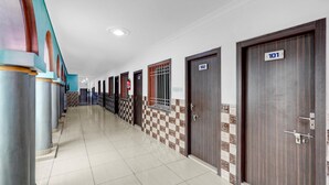 A hotel corridor with numbered doors, check-in counters, and a tiled floor.