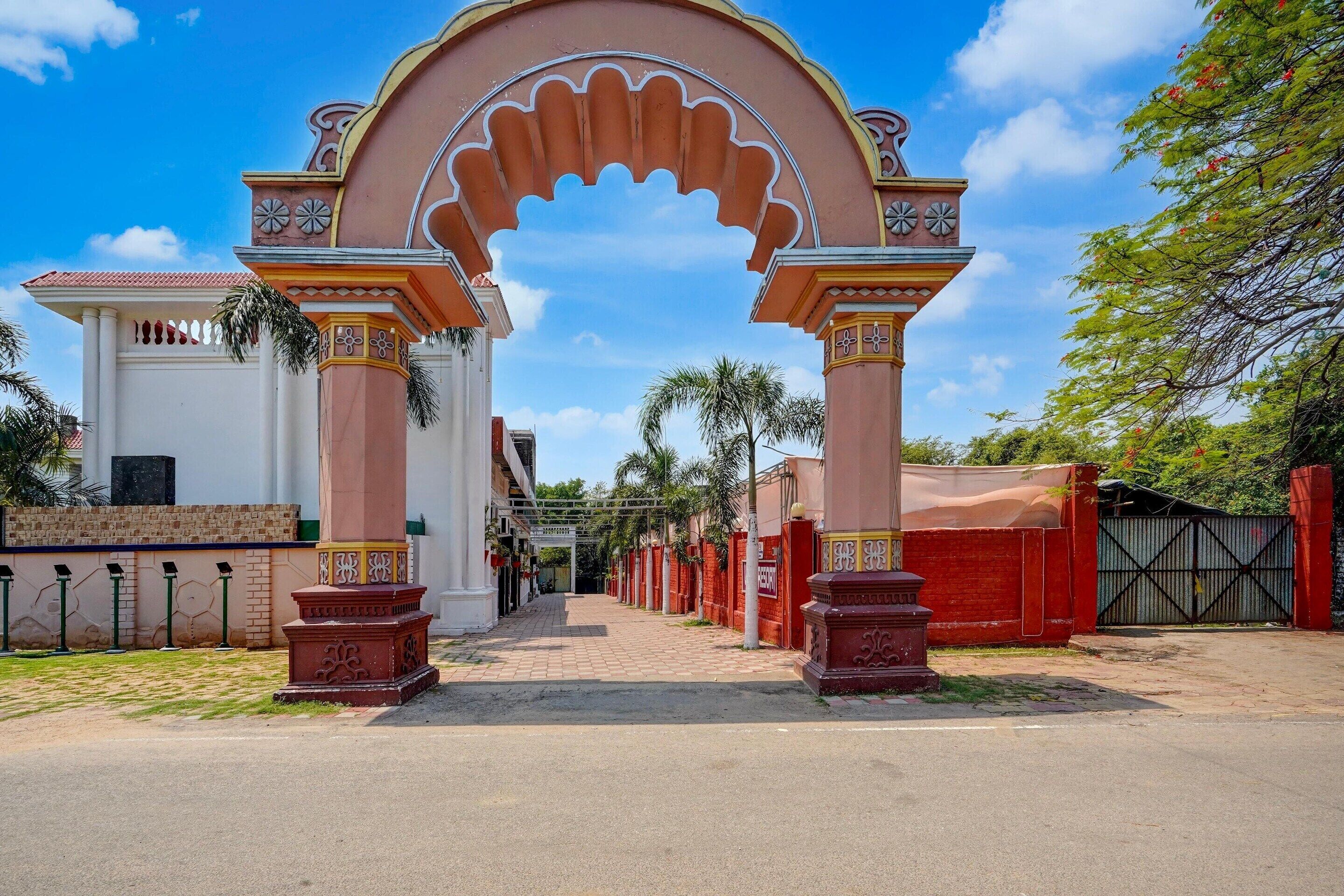 An entrance with an ornate archway, a gated pathway, and a building with a white facade.