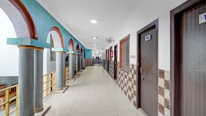A hotel corridor with columns, doors numbered 102, and a checkered wall pattern.