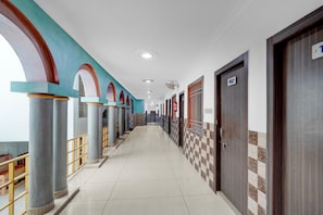 A hotel corridor with columns, doors numbered 102, and a checkered wall pattern.