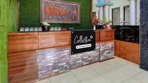 A reception desk with a green wall, a framed artwork, and a sign that reads 'Collection Company-Serviced'.