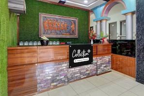 A reception desk with a green wall, a framed artwork, and a sign that reads 'Collection Company-Serviced'.