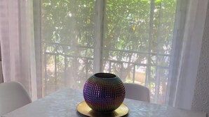 Un tavolo con un oggetto decorativo, una finestra che si affaccia sul verde e una sedia.