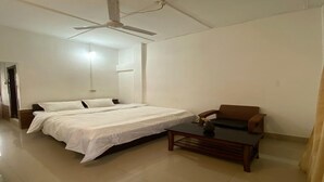 Una camera da letto con un letto, una sedia, un tavolo e una ventola a soffitto.