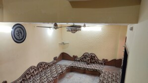A room with a curved sofa, a ceiling fan, and a chandelier.