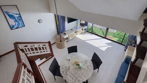 Een modern interieur met een eetgedeelte, een trap en uitzicht op een groene buitenruimte.