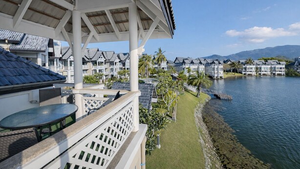 Een resort met uitzicht op het water, een overdekt terras en meerdere gebouwen met balkons.