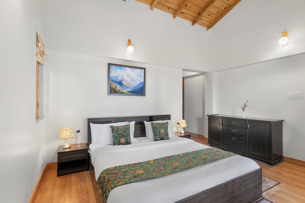 Une chambre à coucher avec un lit, des tables de chevet, une commode, un tableau et un plafond en bois.