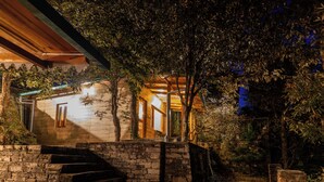 A stone staircase leading to a wooden house with a porch, surrounded by trees. - Alaya Stay Hill Home Petfriendly Cottage (Kosiyakutoli)