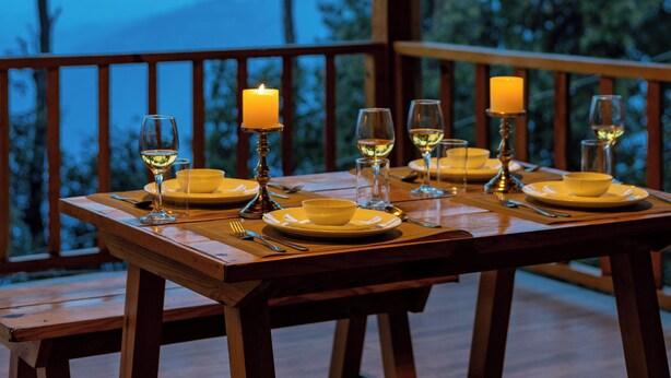 A wooden deck with a table set for a meal, overlooking a mountainous landscape. - Alaya Stay Hill Home Petfriendly Cottage (Kosiyakutoli)