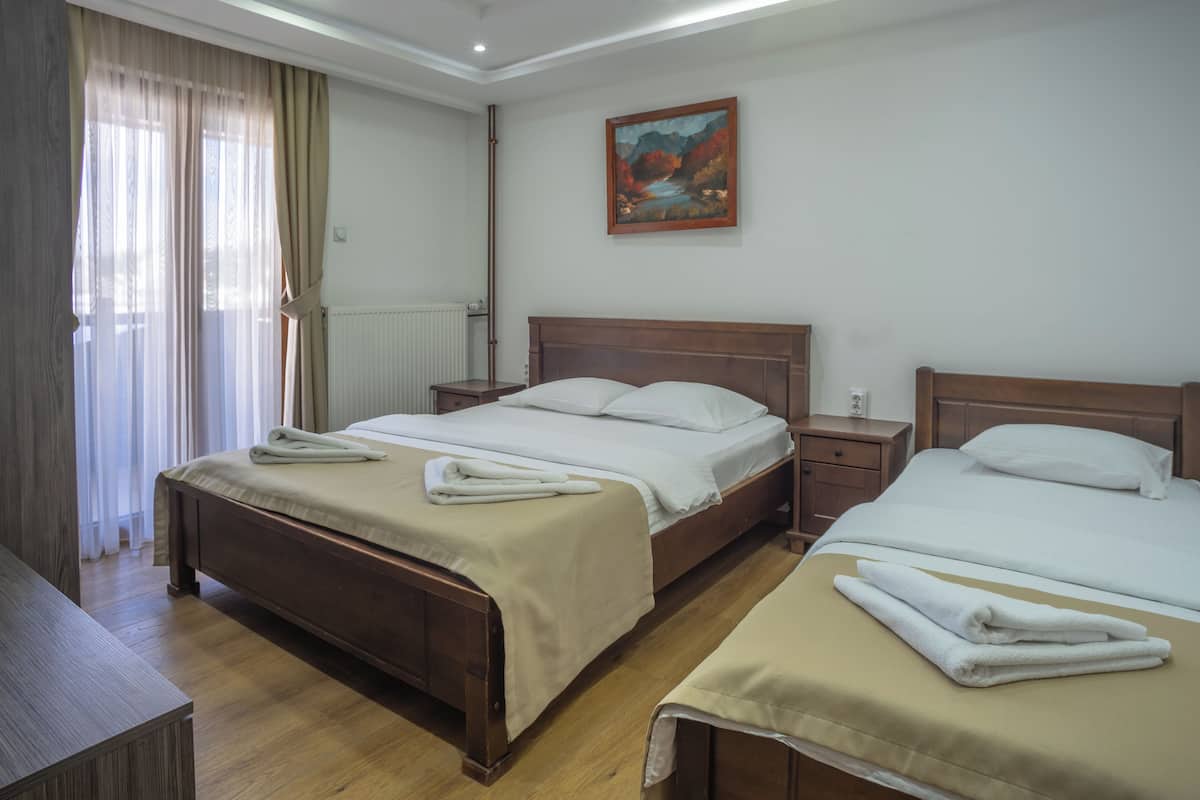 Une chambre d’hôtel avec deux lits, un tableau au mur et une fenêtre avec des rideaux.