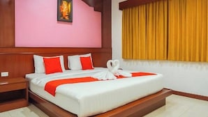 A hotel room with a bed, a nightstand, a headboard, a window with curtains, and a wall-mounted picture.