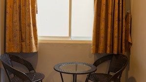A room with a window, two wicker chairs, a small round table, and a curtain with a floral pattern.