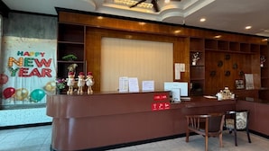 A reception desk with a ceiling fan, a bulletin board, and a 'Happy New Year' decoration.