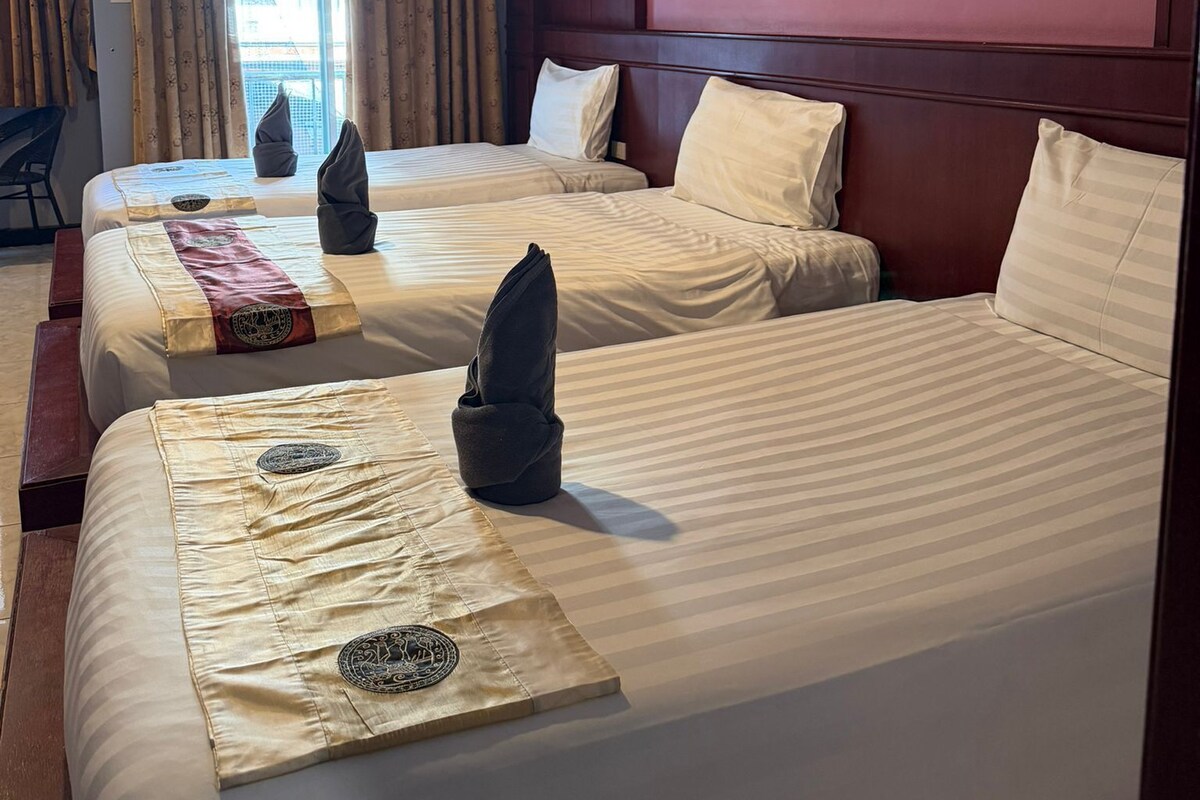 Habitación de hotel con dos camas, una ventana con cortinas, aire acondicionado instalado en la pared y un cuadro enmarcado.