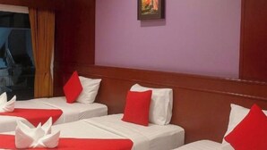 A hotel room with three beds, each with white bedding and red pillows, a painting on the wall, and a window with curtains.