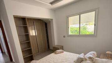Quarto com cama grande, armário embutido e janela com vista para área verde.