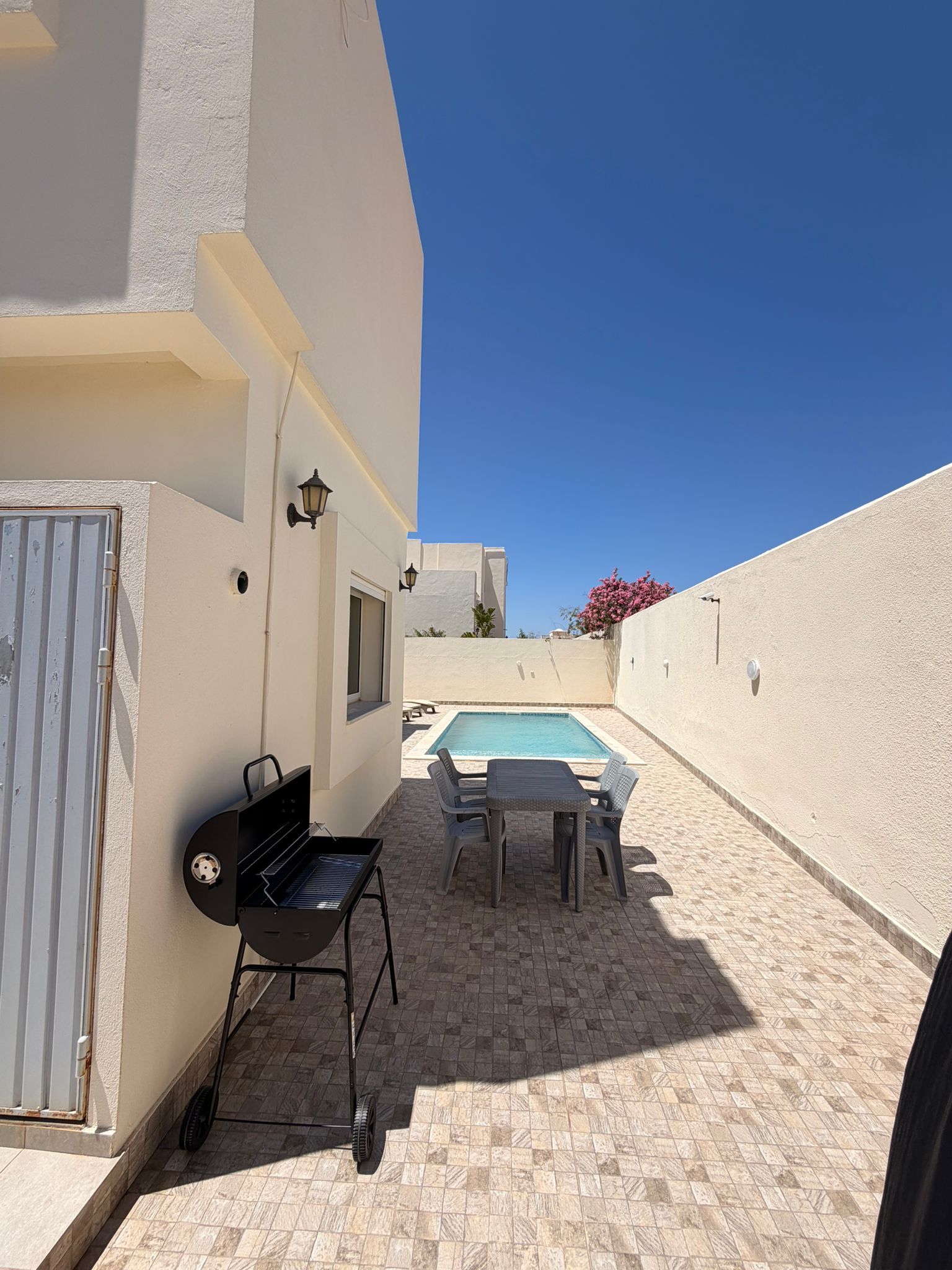 Une terrasse avec un barbecue, une piscine et du mobilier d’extérieur.