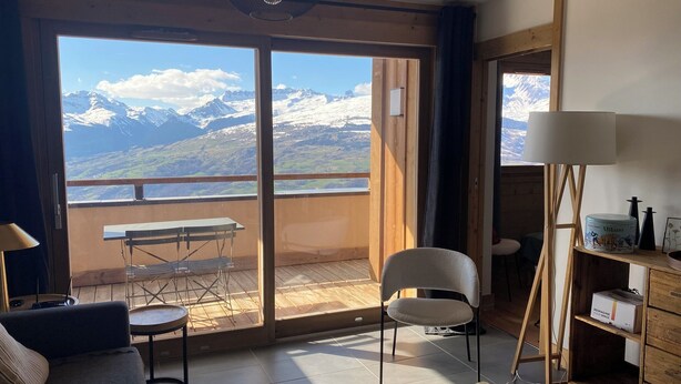 Una habitación con balcón, una mesa, una silla, un sofá y una lámpara.
