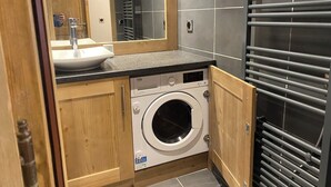 Un baño pequeño con lavamanos, espejo y lavadora.