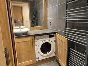 Ein kleines Badezimmer mit Waschbecken, Spiegel und Waschmaschine.