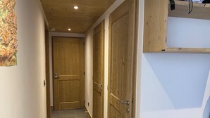 Un pasillo estrecho con puertas de madera y suelo de baldosas.