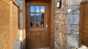 Una puerta de madera con un muro de piedra, una ventana que ofrece vistas a montañas y un buzón pequeño.