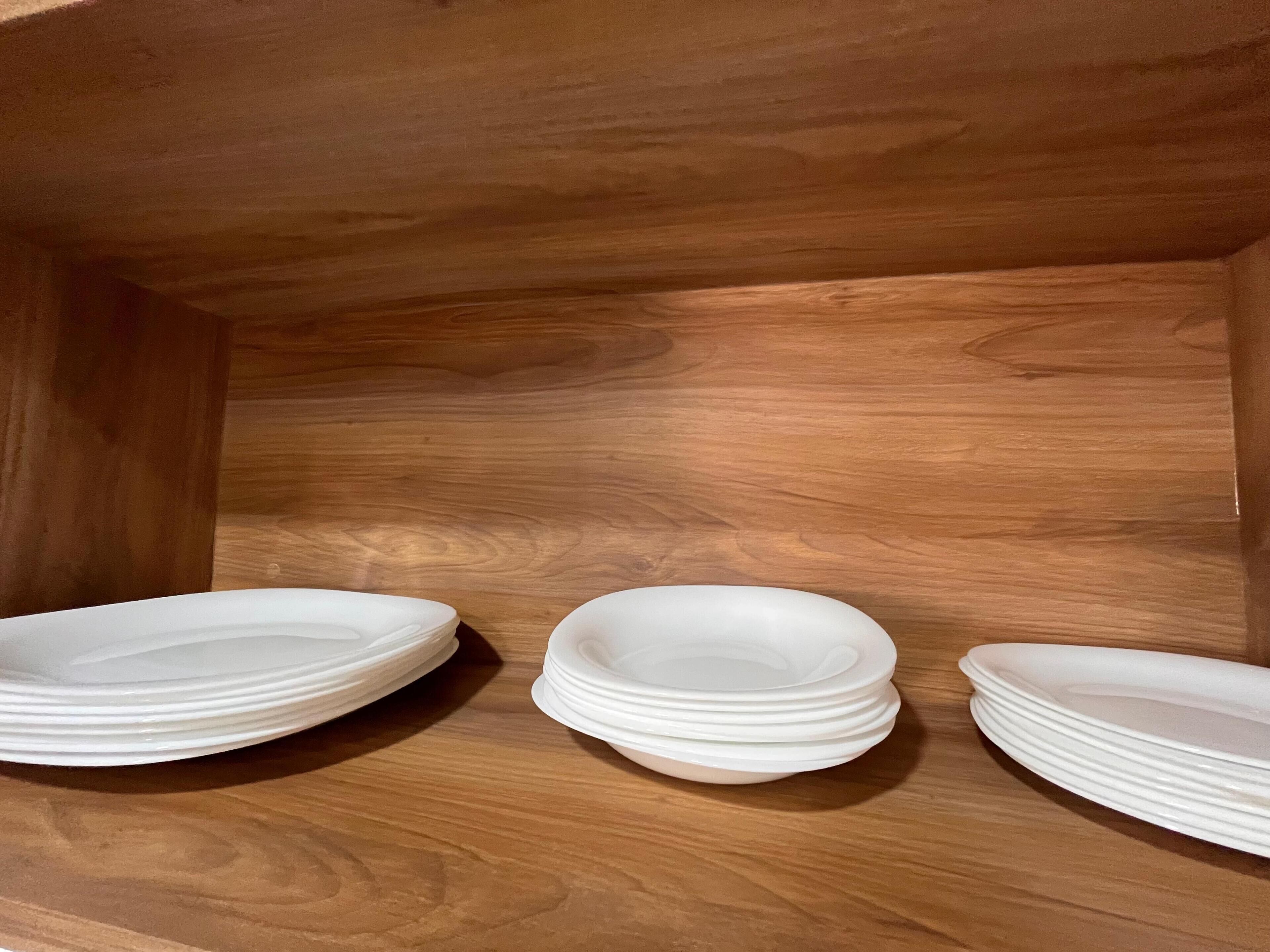 Une étagère en bois sur laquelle sont empilées trois assiettes blanches.