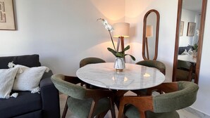 Ein Essbereich mit einem runden Tisch, Stühlen, einer Blumenvase, einer Lampe und einem Spiegel.