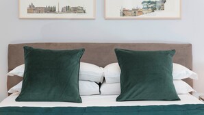 A bed with a brown headboard, two green pillows, and a white comforter. - Design Apartment in Spanish Steps (Roma)