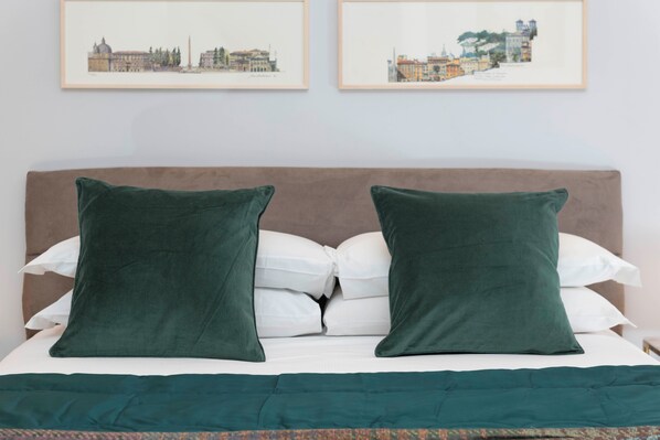 A bed with a brown headboard, two green pillows, and a white comforter. - Designer Apartment Near the Spanish Steps (Roma)