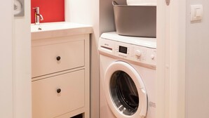 A compact laundry room with a washing machine, a sink, and a mirror. - Design Apartment in Spanish Steps (Roma)