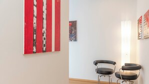 A room with a wooden floor, two black chairs, a red and white artwork, and a small painting on the wall. - Design Apartment in Spanish Steps (Roma)