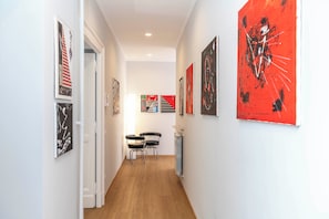 A hallway with artwork on the walls, a radiator, and two chairs. - Design Apartment in Spanish Steps (Roma)