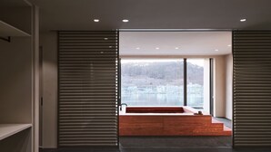 Une chambre d’hôtel moderne avec une grande fenêtre, un banc en bois et un lit.
