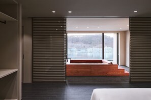 Une chambre d’hôtel moderne avec une grande fenêtre, un banc en bois et un lit.