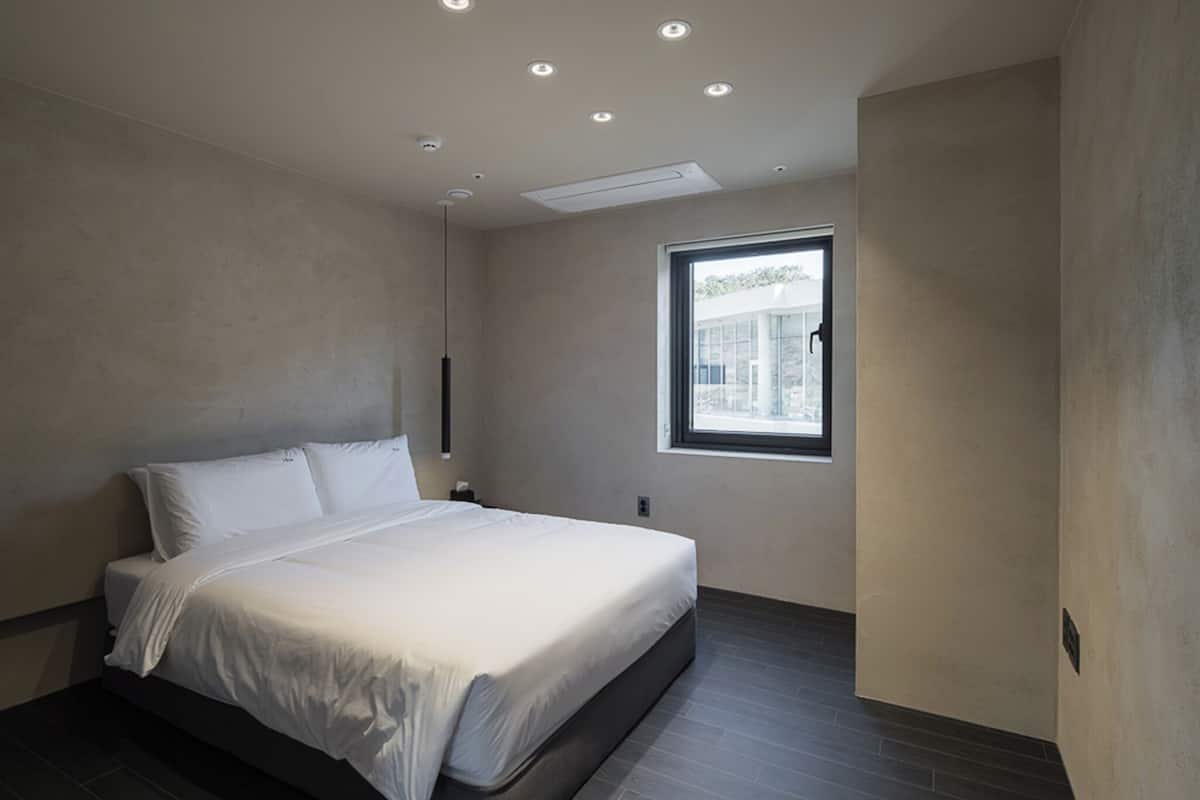 Quarto moderno com cama, janela e iluminação embutida no teto.